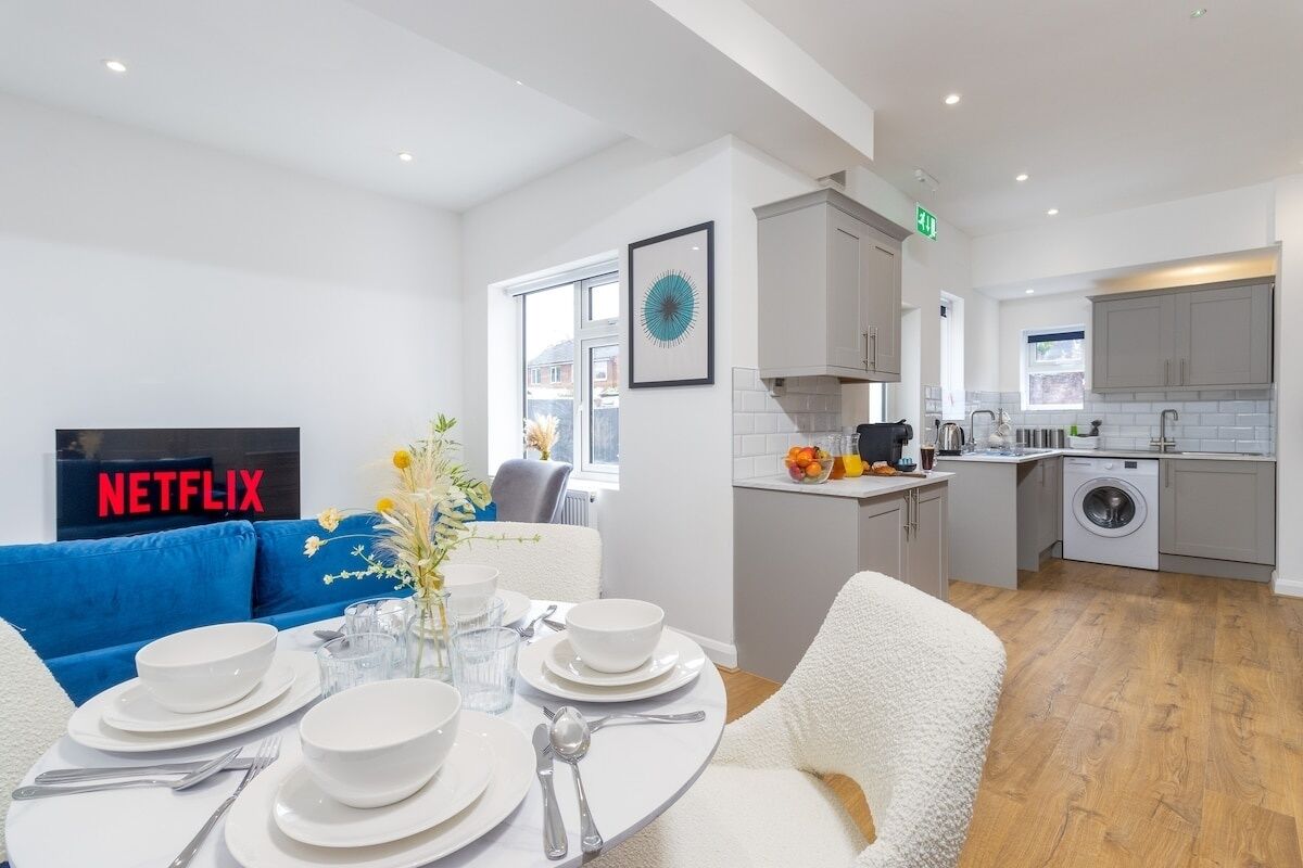 A modern kitchen with white cabinets, a built-in oven, and a washing machine.
