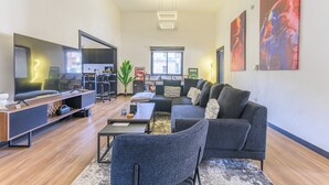 A modern living room with a large flat-screen TV, a sofa, a coffee table, and a dining area. - Residence 4 - Apartments in Mar Mikhael (Beirut)