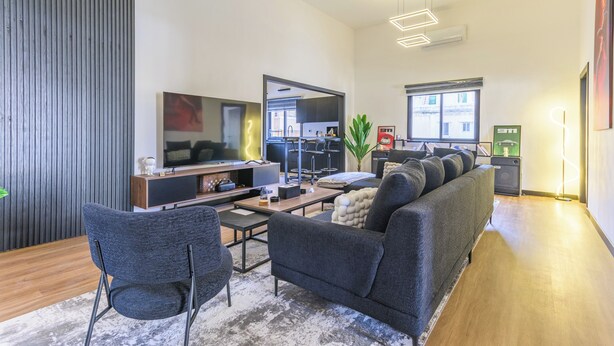 A modern living room with a sofa, a TV, a coffee table, and a dining area. - Residence 4 - Apartments in Mar Mikhael (Beirut)