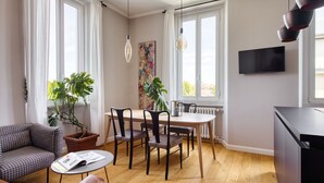 Ett modernt vardagsrum med en soffa, ett matbord, stolar, ett soffbord och två krukväxter.
