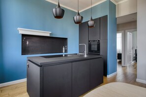 A modern kitchen with a central island, a built-in oven, and pendant lighting. - Hostmate - Milano - Viale Zara  (Milano)