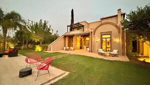 Una casa moderna con patio, area salotto esterna e prato curato.