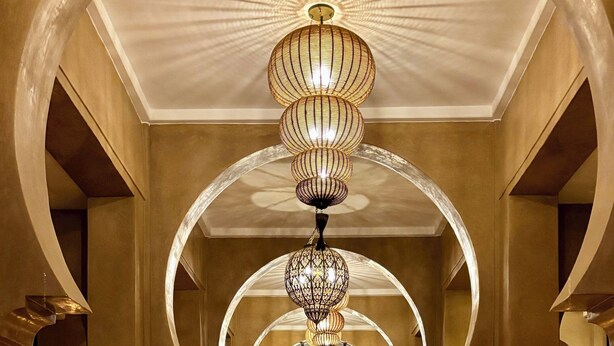 Un'imponente galleria ad arco con un lampadario, che conduce a un'area reception con vista all'esterno.