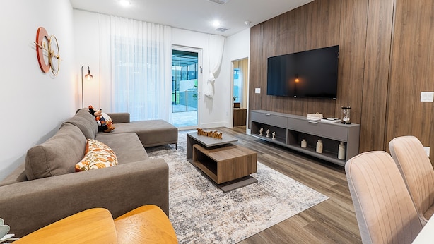 Una sala de estar moderna con sofá, mesa de centro, televisor y paneles de madera.