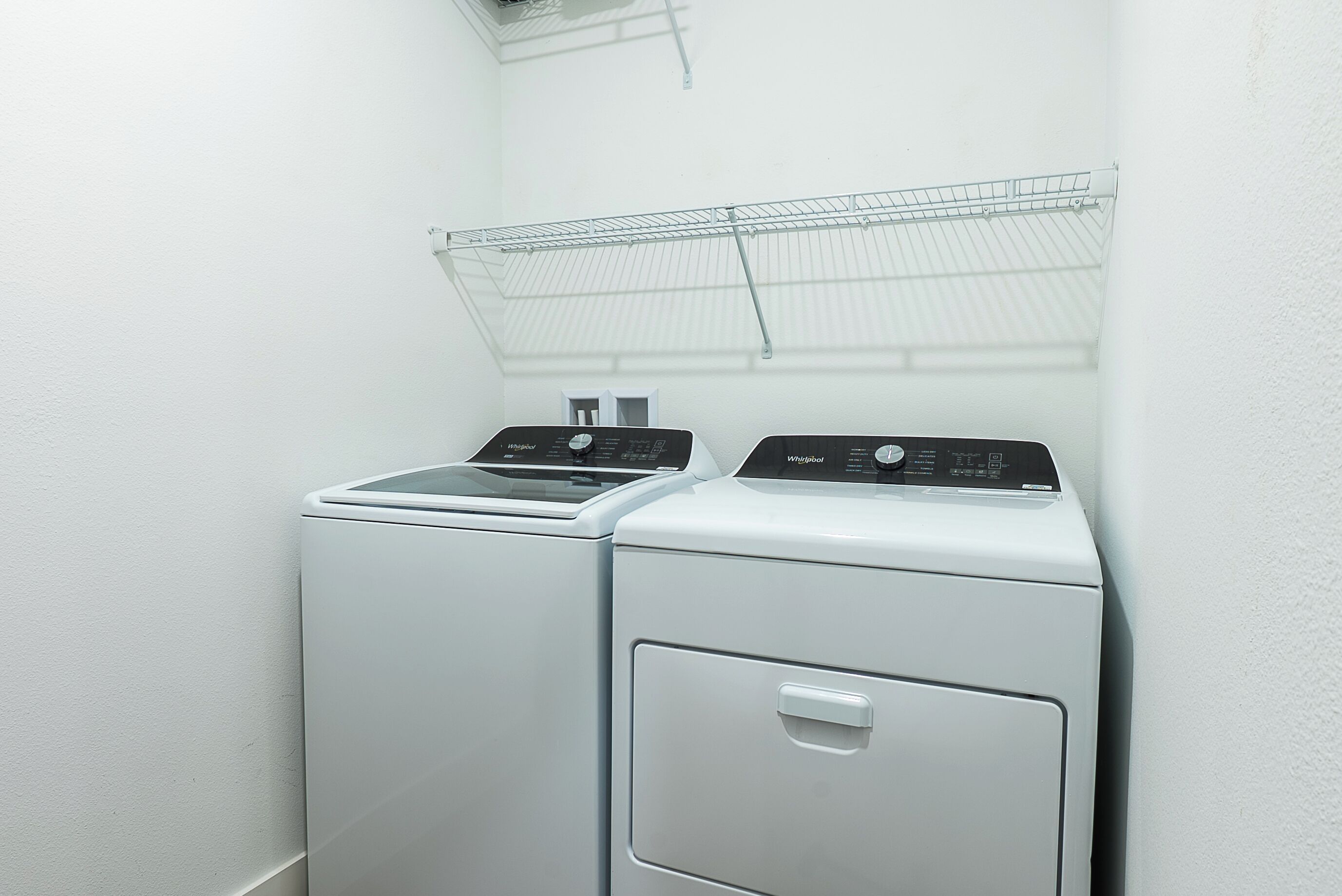 A laundry area with two front-loading washers and a metal drying rack above them.