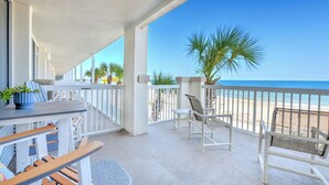 Un espace extérieur abrité, avec vue sur la plage, comprenant une table avec des chaises, un banc et des plantes en pot.