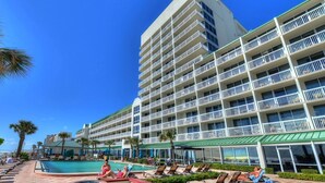 Un hotel con zona de piscina, varios balcones y vista al océano.