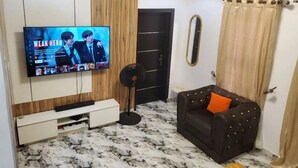 Una sala de estar con televisor, sofá, ventilador y puerta.