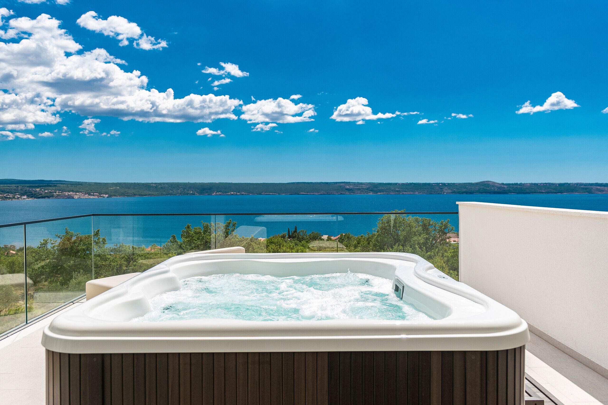Un jacuzzi en un balcón con vistas a un lago y montañas.