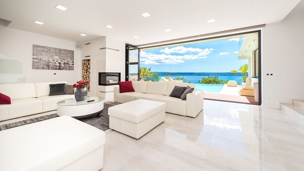 A modern living room with a large glass door leading to a balcony with a view of the sea. - Villa Michelle with infinity pool (Maslenica)
