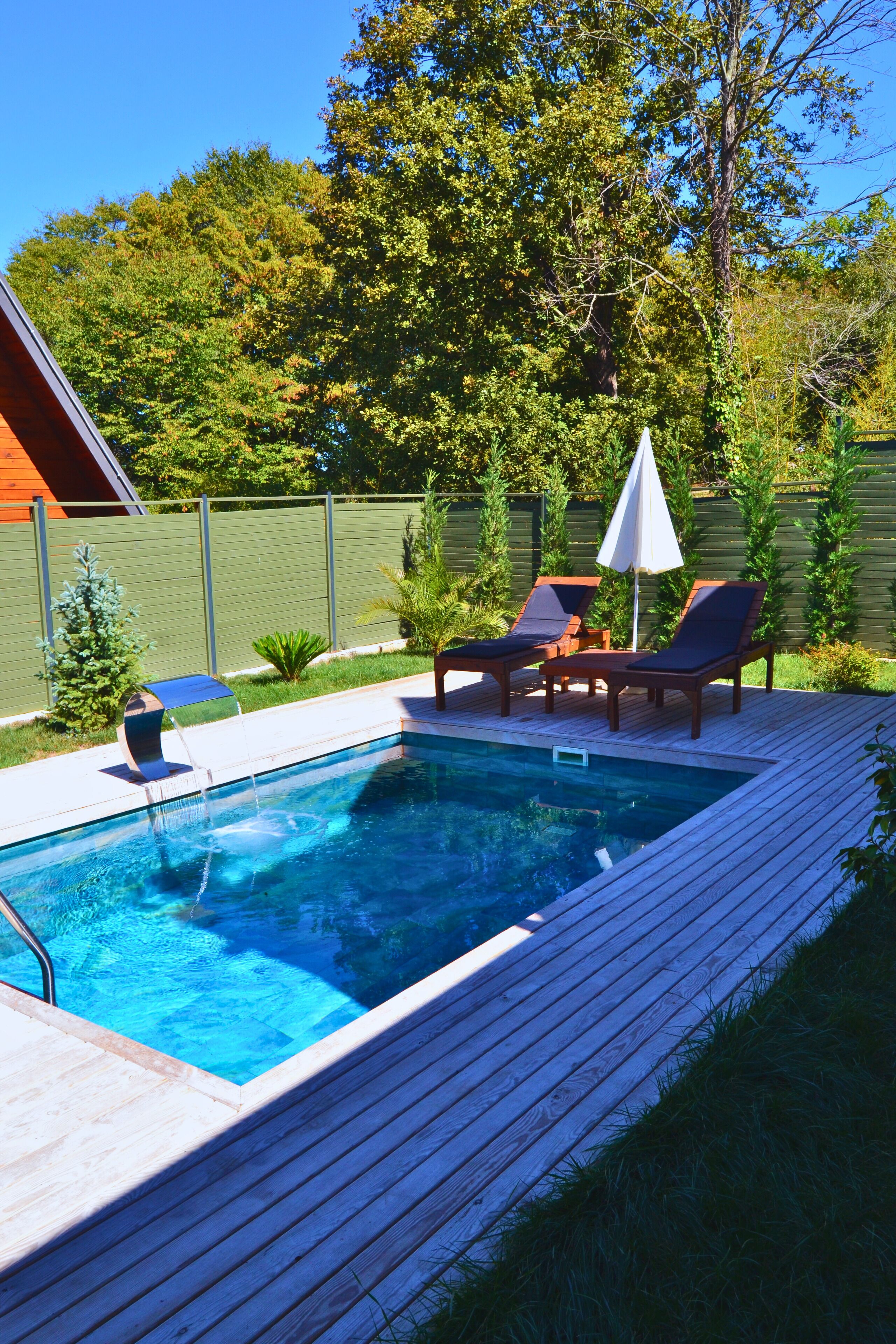 Una piscina al aire libre, sombrillas, sillones reclinables de piscina