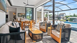 Ein moderner Außenbereich mit Korbmöbeln, einem Holztisch und Blick auf einen Swimmingpool.