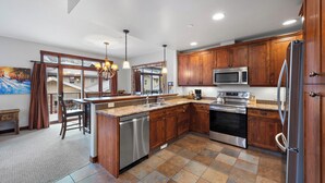 A modern kitchen with wooden cabinets, stainless steel appliances, and a large island. - Spacious, Multi-Floor 4bedroom Townhome Walking Distance to Village, Along Orient Chairlift! (Sun Peaks)