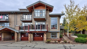 A multi-story building with a stone facade, multiple balconies, and a front entrance with a wooden door. - Spacious, Multi-Floor 4bedroom Townhome Walking Distance to Village, Along Orient Chairlift! (Sun Peaks)