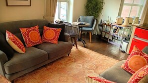 Een woonkamer met een grijze bank, gestreepte kussens, een ronde salontafel en een grijze fauteuil.