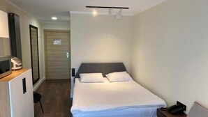 A hotel room with a bed, bedside table, chair, and a desk with a computer. - Lovely 1-bedroom apartment in Bakuriani perfect for a cozy getaway (Bakuriani)