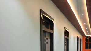 A hallway with three elevator doors, a polished marble floor, and recessed lighting along the ceiling. - Radhe Palace (Ayodhya)