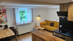 Een moderne keuken met een zwarte kookplaat, houten kastjes en een eethoek met een tafel en stoelen.