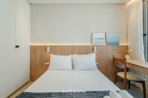 A neatly arranged bedroom with a bed, a wooden headboard, a desk, and a chair. -  Apt w/ Barbecue Grill 50 m from the Beach DOI0203 (Florianópolis)