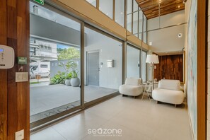 A modern interior with a reception area, a seating area, and a view of the street outside. -  Apt w/ Barbecue Grill 50 m from the Beach DOI0203 (Florianópolis)
