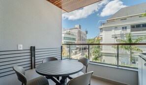 A balcony with a round table and chairs, a power outlet, and a view of surrounding buildings. -  Apt w/ Barbecue Grill 50 m from the Beach DOI0203 (Florianópolis)