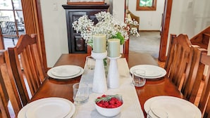 Een eettafel gedekt met witte borden, glazen en een schaal met frambozen en rozemarijn.