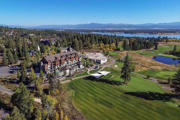 A lodge with multiple buildings, a golf course, and a lake in the background.