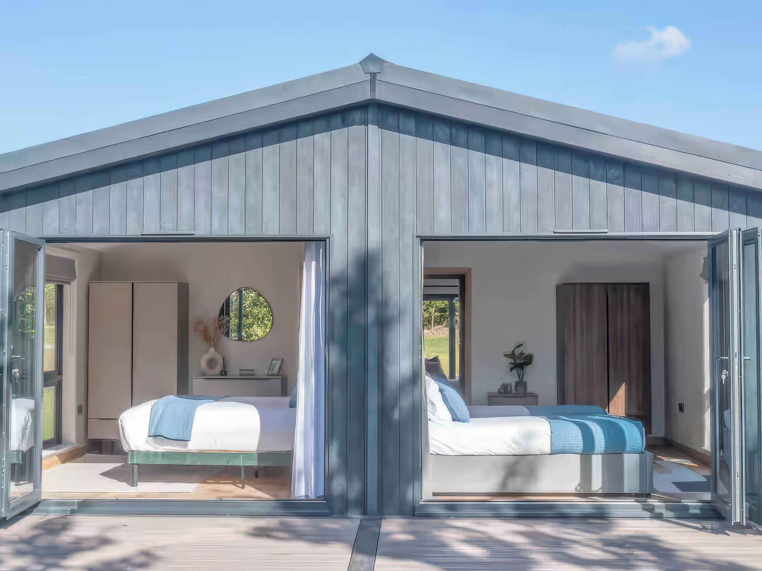A modern, two-room cabin with a sloped roof, large windows, and a view of the outdoors.