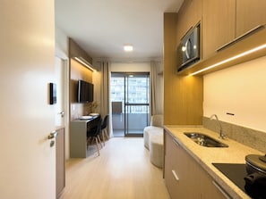 A modern kitchen with a built-in microwave, a sink, and a dining area with a table and chairs. - Nex One Vila Nova Conceição (São Paulo)