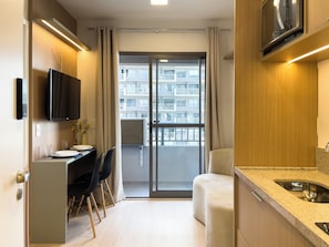A modern hotel room with a kitchenette, a dining area, and a balcony with a view of the building. - Nex One Vila Nova Conceição (São Paulo)