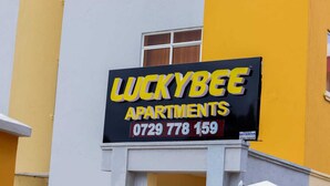 Un cartel que indica 'LUCKYBEE APARTMENTS' con un número de contacto.