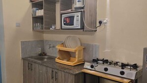 Una cocina compacta con microondas, estufa a gas y un lavamanos pequeño.