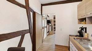 A narrow kitchen with wooden beams, a sink, and a stove.
