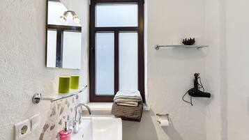 A bathroom with a white sink, a mirror, a towel rack, and a window.