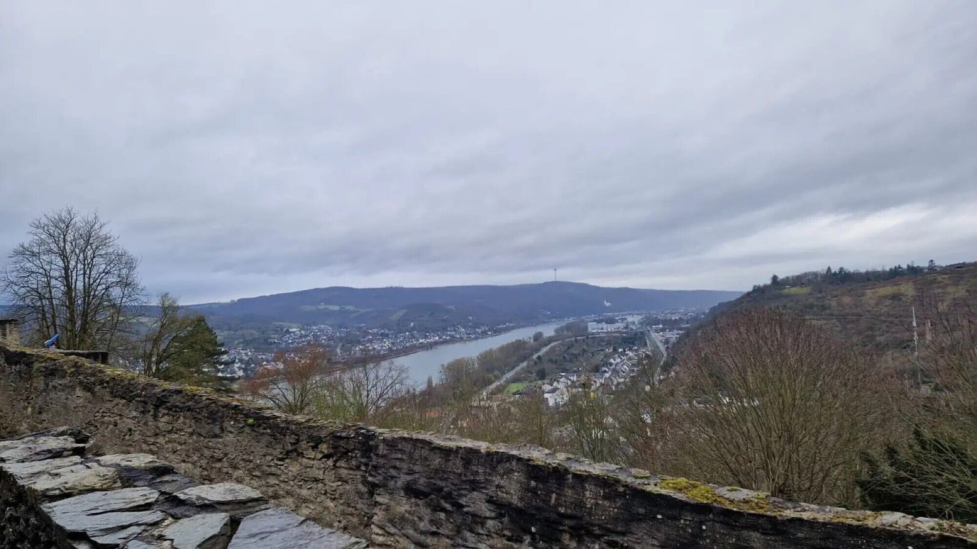 Un mur de pierre offrant une vue sur une rivière et une ville au loin.