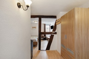 A hallway with a wooden wardrobe, a bed, and a dining area. - Guest House 'Apartment 3' with Shared Terrace (Braubach)
