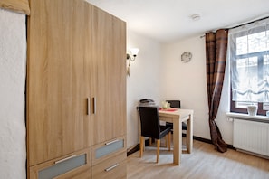 A room with a wooden wardrobe, a table with chairs, a wall clock, and a window with curtains. - Guest House 'Apartment 3' with Shared Terrace (Braubach)