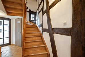 Eine Holztreppe mit Blick auf einen Raum, der eine Tür und ein Fenster zeigt.