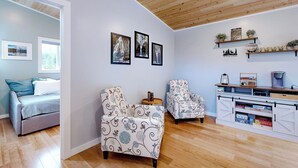 A living room with a sofa, two armchairs, a coffee table, and a wooden cabinet with shelves. There are framed pictures on the wall and a window with blinds. - Fire Pit & Mtn Views! Cabin $1 Cleaning Fee (Carson)