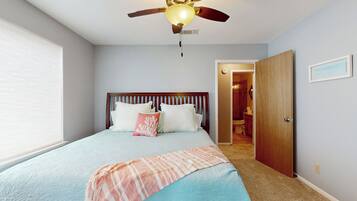 A bedroom with a bed, a ceiling fan, a door, and a window.