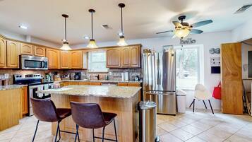 Una cocina moderna con armarios de madera, electrodomésticos de acero inoxidable y una isla central con taburetes de bar.