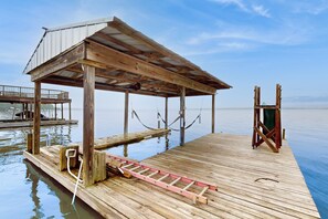 A wooden pier with a covered seating area and a lifebuoy.