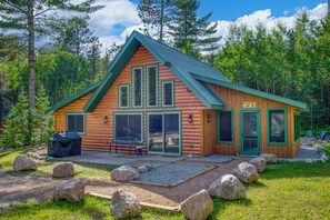 Une cabane en rondins avec un toit végétalisé, de grandes fenêtres et une enseigne sur laquelle on peut lire : « Le repaire de Dawson ».