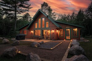 Une cabane en rondins avec un porche, de grandes fenêtres et une enseigne sur laquelle on peut lire : « Le repaire de Dawson ».
