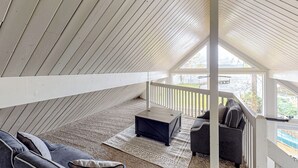 Une chambre aménagée dans les combles, avec un plafond en pente, un banc en bois, un canapé et une vue sur une piscine.