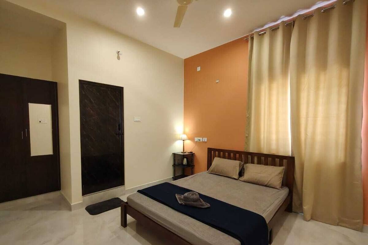 Ein Hotelzimmer mit Bett, Nachttisch, Lampe und Tür.