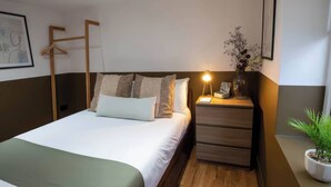 A neatly arranged hotel room with a bed, bedside tables, a lamp, and a potted plant. - Fir Cottages (Llanrwst)