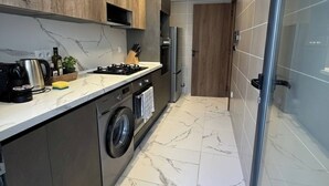 A narrow kitchen with a washing machine, a stove, and a refrigerator. - Luxurious 2-bedroom Apartment in Heart of Rabat (Rabat)