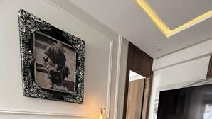 A dining area with a glass table, black chairs, a fruit bowl, a framed picture, and a TV mounted on the wall. - Luxurious 2-bedroom Apartment in Heart of Rabat (Rabat)