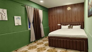 Une chambre à coucher avec une tête de lit en bois, un parquet à motifs et des murs verts.